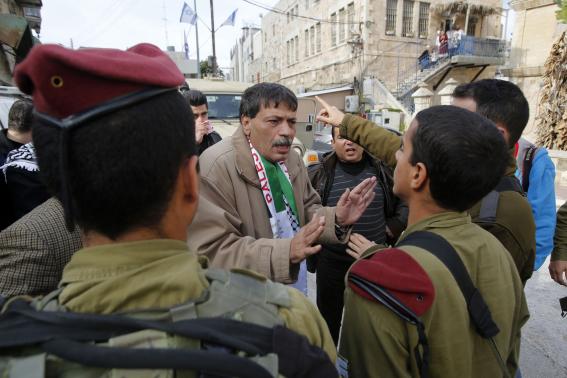 Palestinian Ziad Abu Ein, Head of the Anti-wall and Settlement Commission, argues with Israeli soldiers as they prevent him from crossing to Al-Shuhada Street in the West Bank city of Hebron