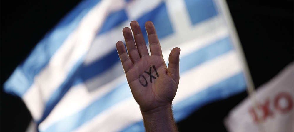 A demonstrator rises his hand reading the word ''No'' as a Greek flag waves during a rally organized by supporters of the No vote in Athens, Friday, July 3, 2015. A new opinion poll shows a dead heat in Greece's referendum campaign with just two days to go before Sunday's vote on whether Greeks should accept more austerity in return for bailout loans. (AP Photo/Petros Giannakouris)/XTS181/346019185476/1507032125